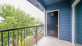 a balcony with a door to a blue building and a tree